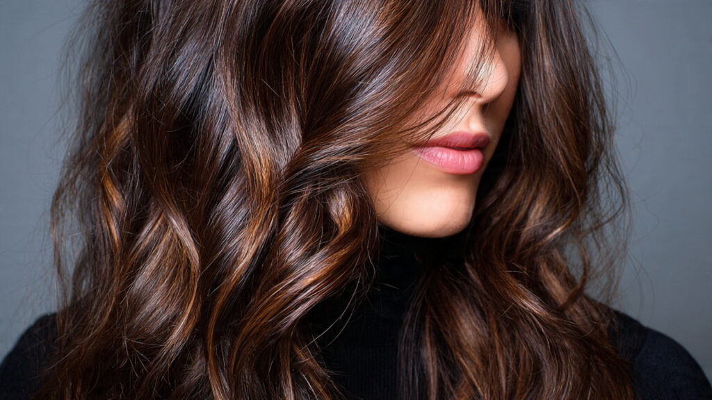 Brunette hair styles with caramel balayage and layered waves.