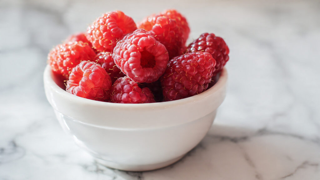 Bowl of raspberries high in fiber fruit for weight loss snacks.
