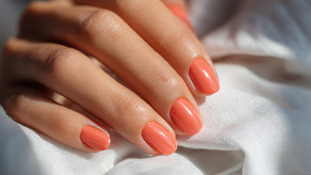 Peach coral March nails with glossy spring finish.