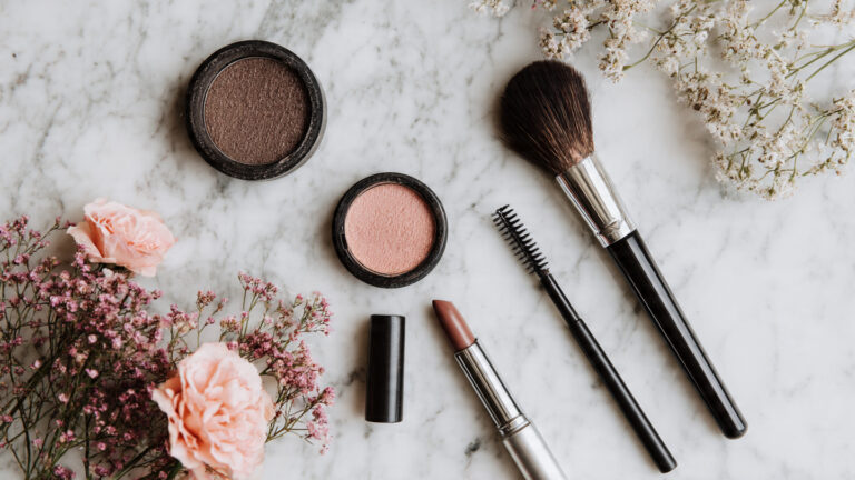 Essential products for quick 10 minute makeup ideas for busy days arranged on neutral background.